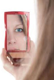A woman looking in the mirror to see if she has a problem on her face.